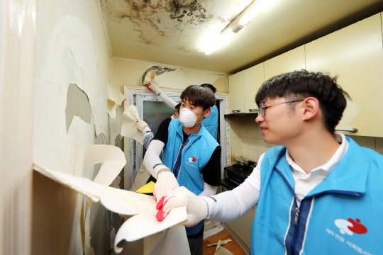 희망의 집 고치기 봉사활동에 나선 대우건설 직원들이 노후된 벽지를 제거하고 있다. <대우건설 제공>